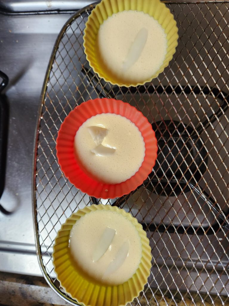 Massa de pão de queijo em forminhas de silicone com recheio de queijo picado no centro.