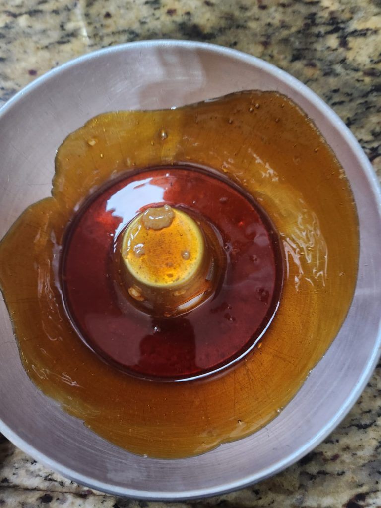 Calda de açúcar caramelizada dourada e brilhante sendo espalhada dentro da forma de pudim de 20cm, untando o fundo e as bordas